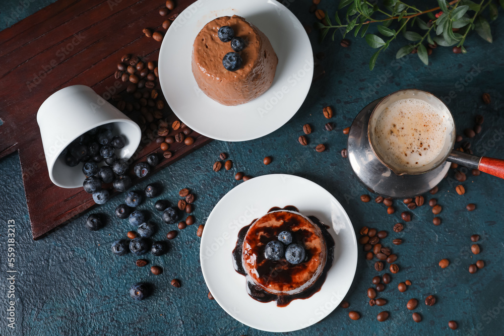 Plates with delicious chocolate pudding, overturned cup of blueberry, coffee beans and cappuccino in