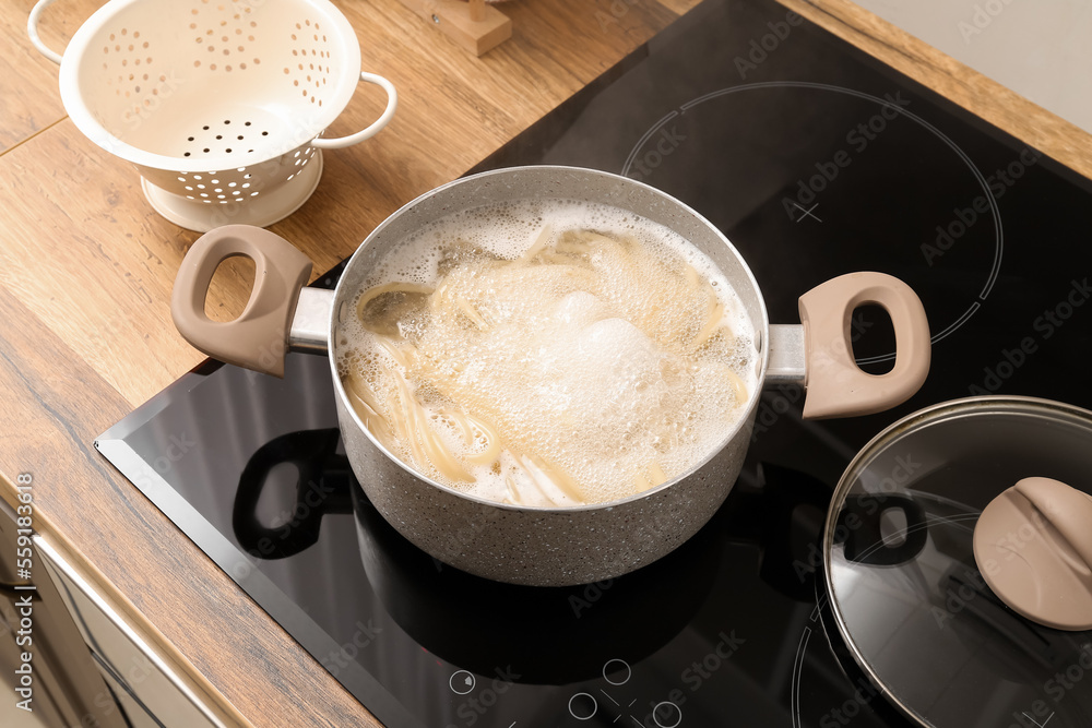 Cooking pot with boiling pasta on electric stove in kitchen