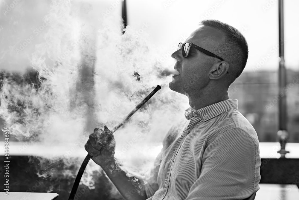 Portrait of adult relaxing and smoking. Handsome man smoking hookah.