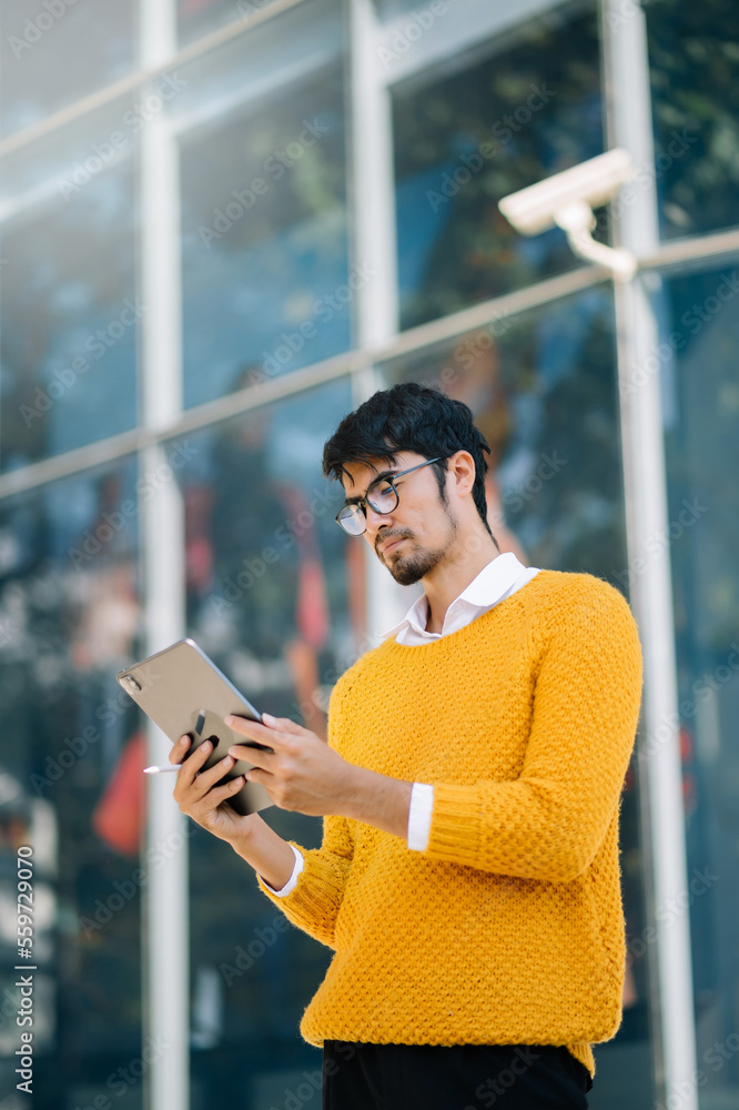  Businessman is embracing and holding a tablet while posing in front of a building