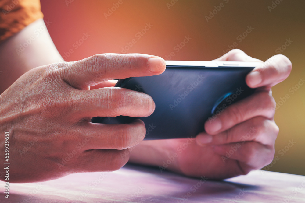 Closeup two hands hold smartphone on table to play game or social media.