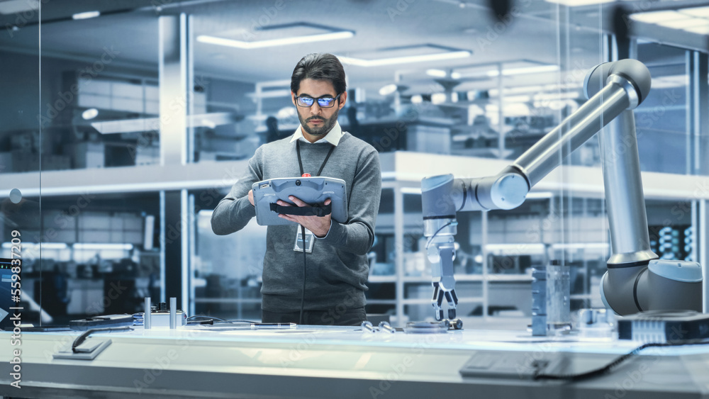 Robotics Engineer Researching and Developing a Technological Robot Arm Project, Standing with Tablet