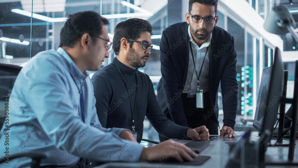 Team of Three Handsome Talented Young Engineers Use Computer to Discuss a Technological Project in I