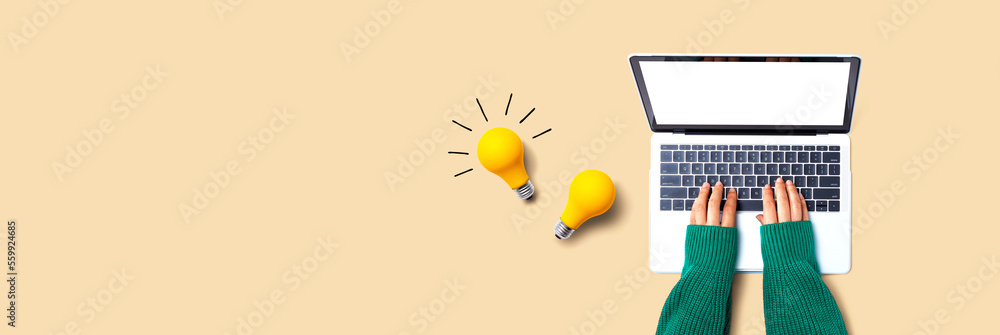 Person using a laptop computer and light bulbs - Flat lay