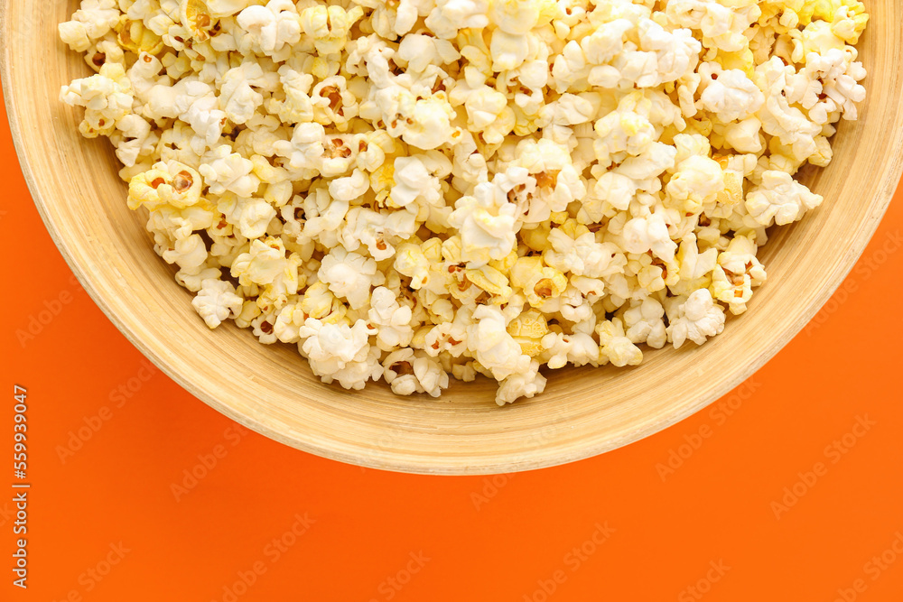 Bowl of delicious popcorn on color background, closeup