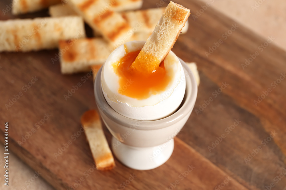 Holder with soft boiled egg and toasted bread on board