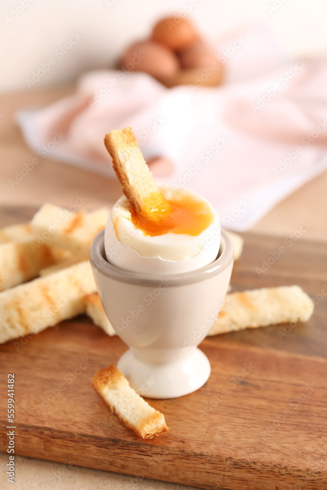 Holder with soft boiled egg and toasted bread on board