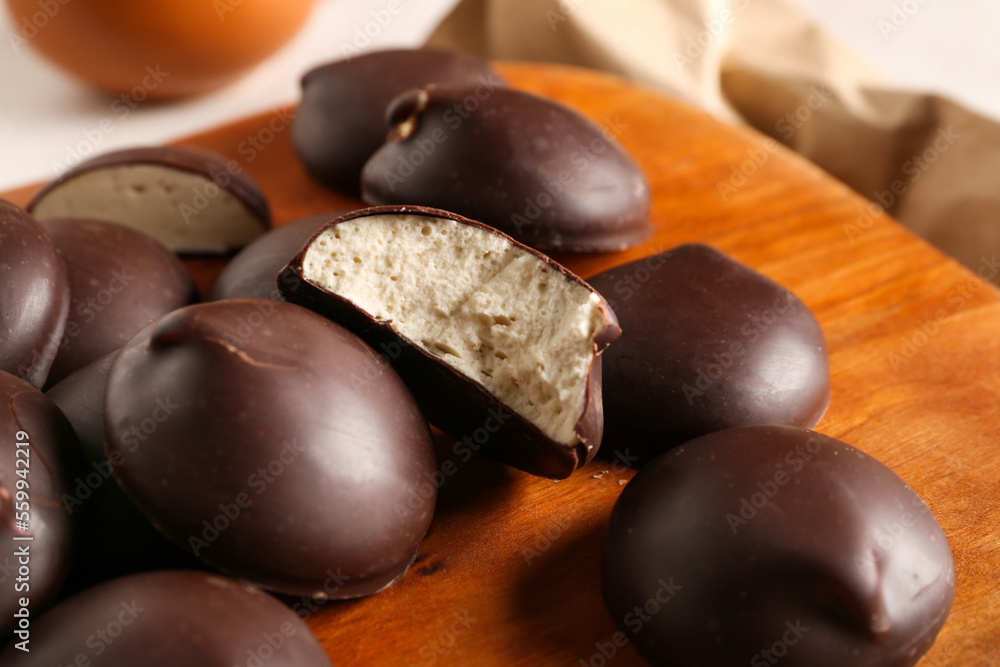 Wooden board with sweet chocolate birds milk candies, closeup