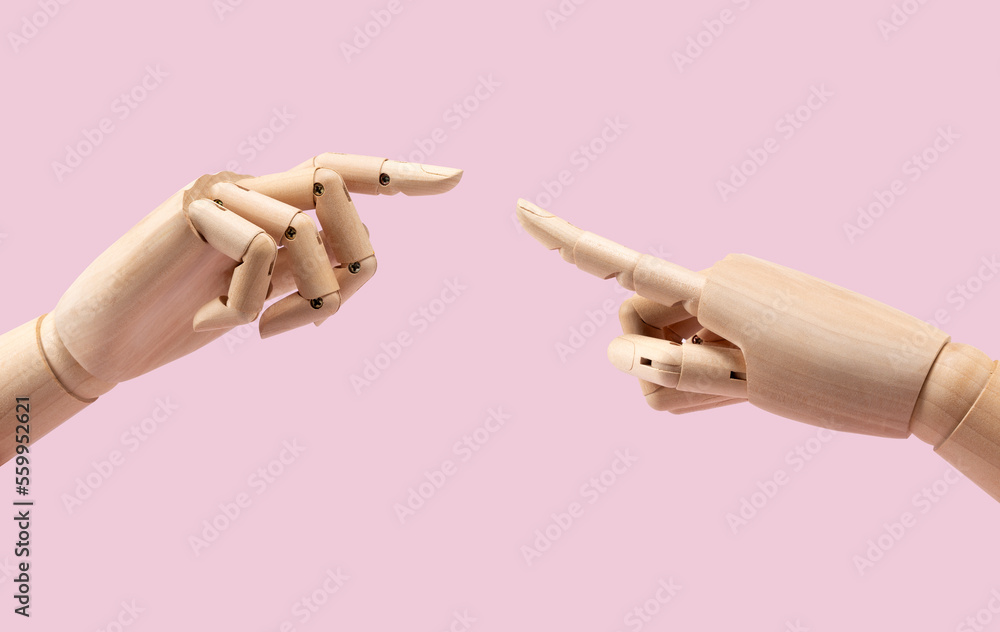 Two wooden mannequin hands on pink background. Fingers together.