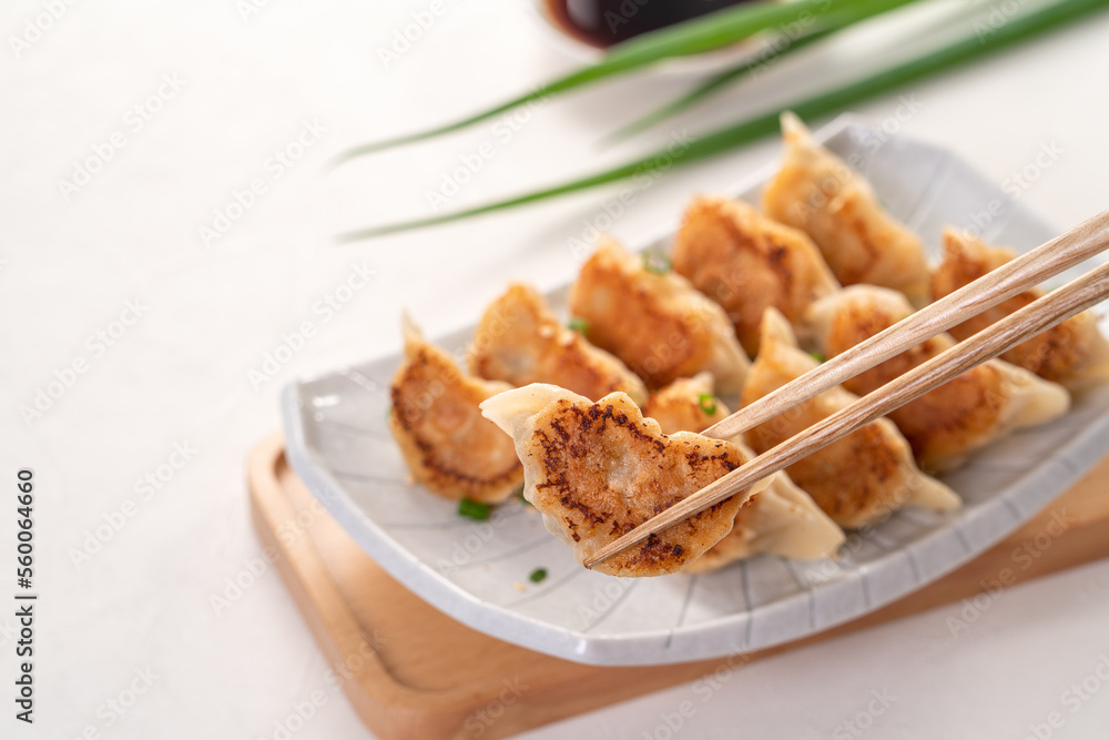 用酱油在白色桌子背景上的盘子里煎饺子饺子饺子。