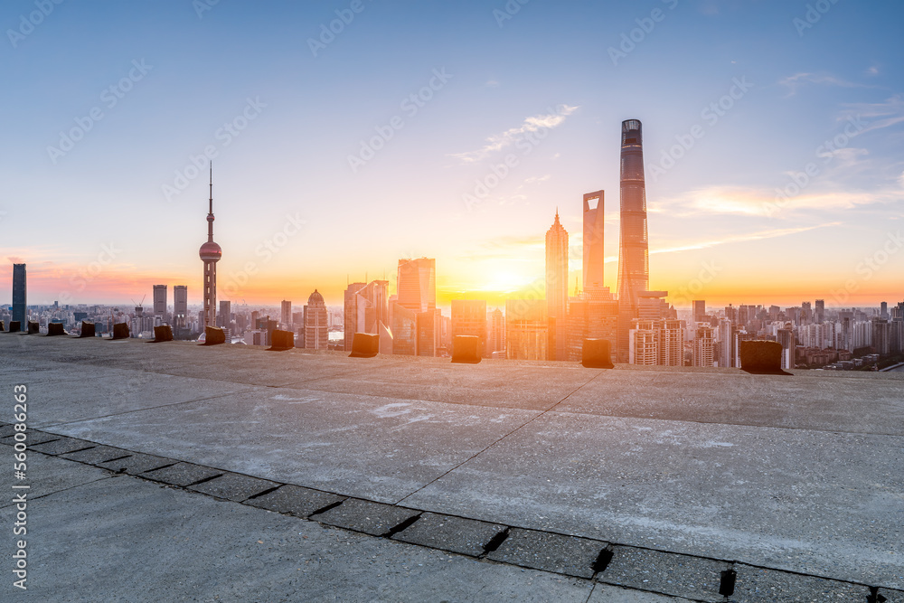 Empty concrete road and city skyline with modern buildings at sunrise in Shanghai, China.