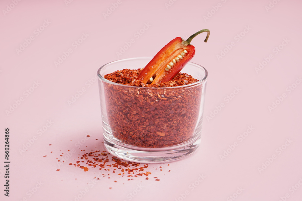 Bowl of chipotle chili flakes on pink background