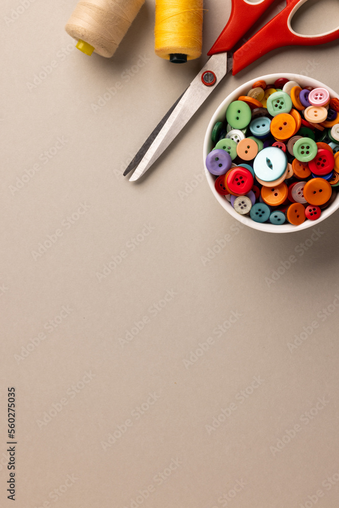 Image of close up of scissors, buttons and threads and copy space on cream background