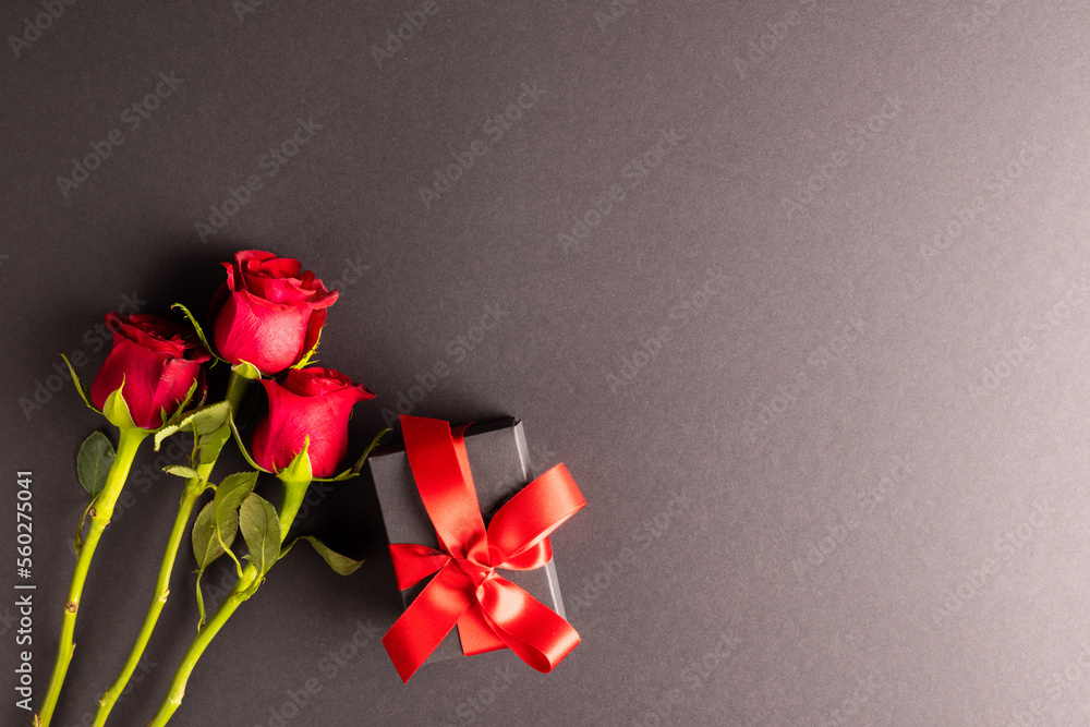 Image of close up of red roses and present and copy space on black background