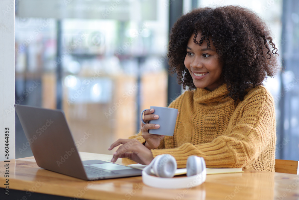 Portrait of young african woman working with laptop and reading books preparing for exams at her hom