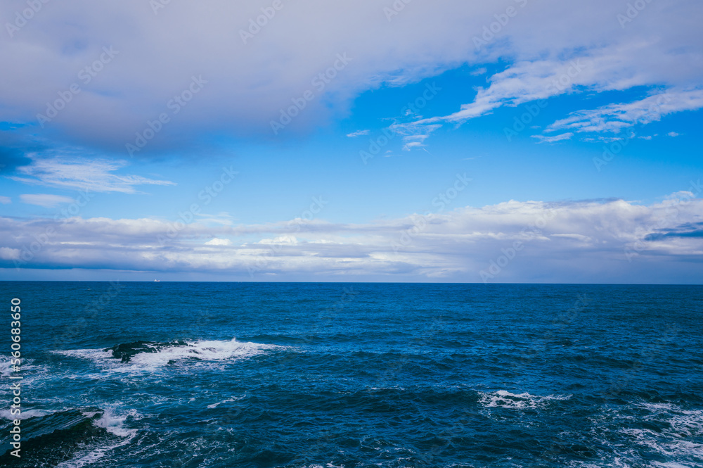 Rocky shore under blue sky and white clouds. White waves and moving white clouds Waimushan Seaside S