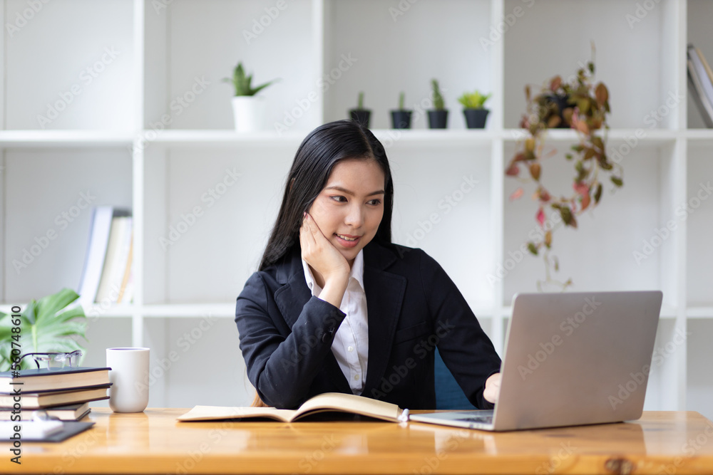 美丽的亚洲女商人在办公室用笔记本电脑工作的肖像。