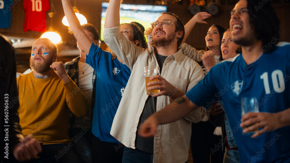 Group of Soccer Fans Watching a Live Football Match Broadcast in a Sports Pub on TV. People Cheering