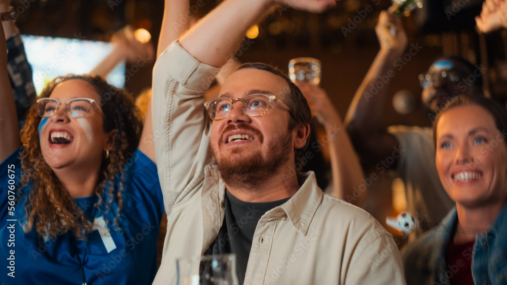 Group of Soccer Fans Watching a Live Football Match Broadcast in a Sports Pub on TV. People Cheering