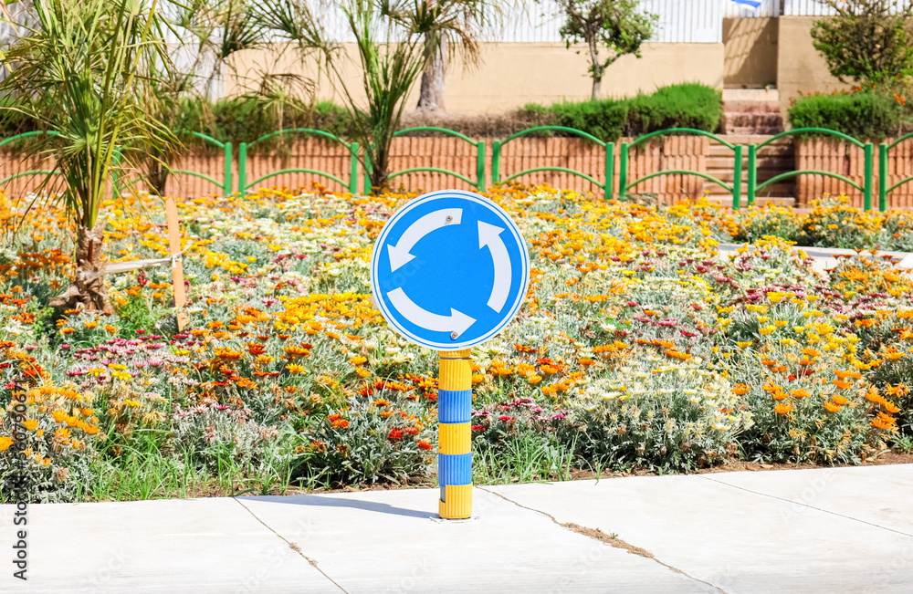 Circular motion sign and flowers on city street