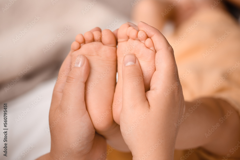 Mother massaging her babys feet in bedroom, closeup