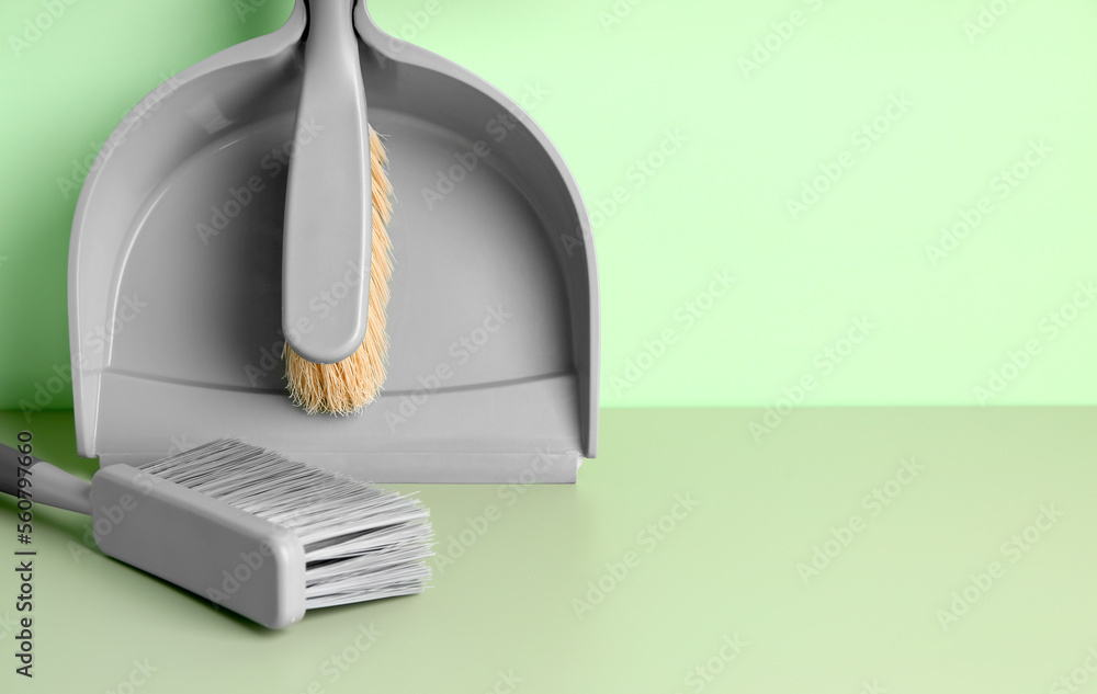 Dustpan and brushes on green background