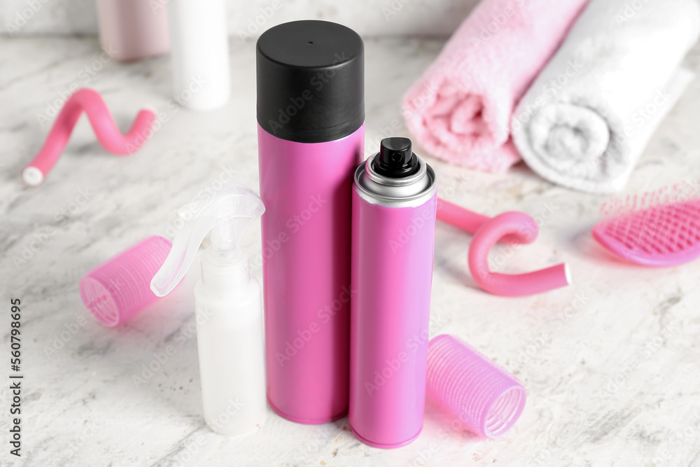 Hair sprays with curlers on light table, closeup