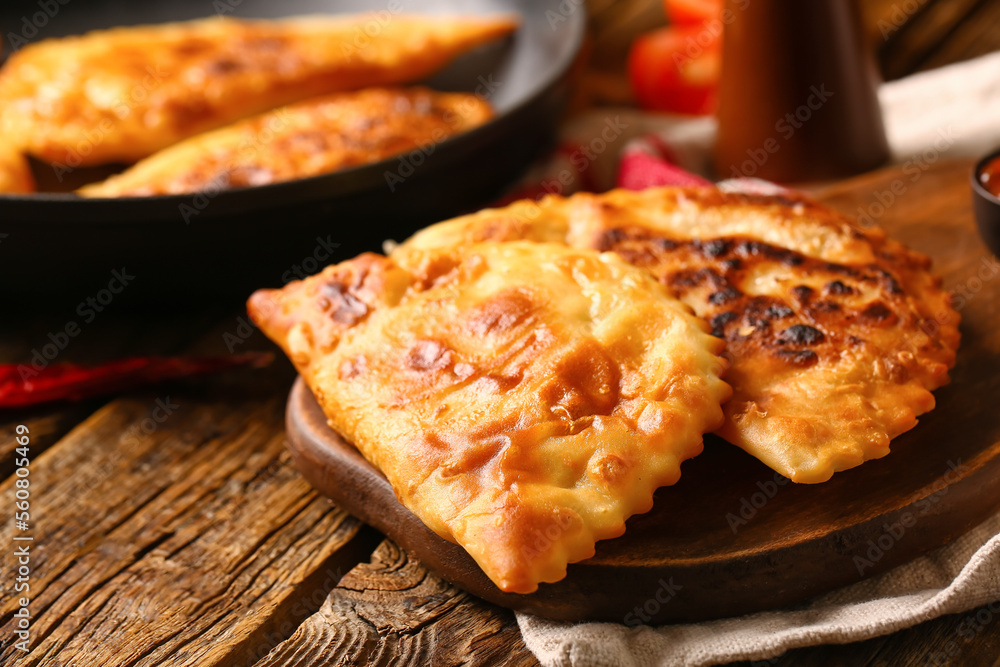 Board with tasty chebureks on wooden background