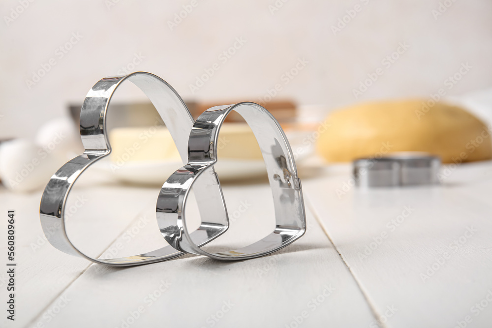 Heart shaped cookie cutters on light wooden table, closeup. Valentines Day celebration