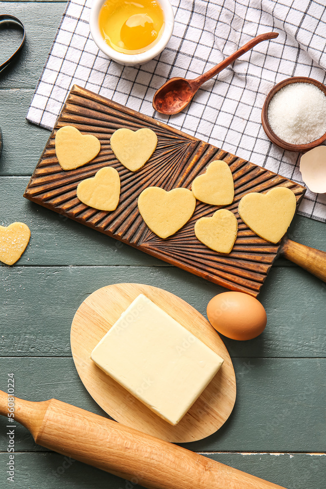 Board with raw heart shaped cookies and ingredients on dark wooden background. Valentines Day celebr