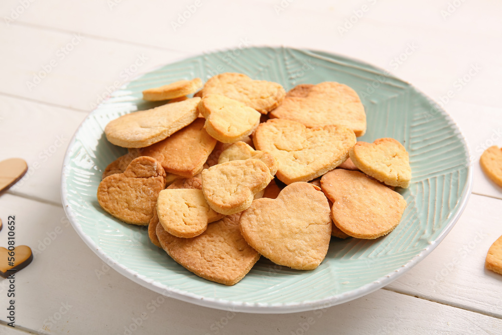 Plate with tasty heart shaped cookies on light wooden background, closeup. Valentines Day celebratio