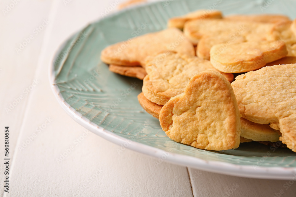 Plate with tasty heart shaped cookies on light wooden background, closeup. Valentines Day celebratio