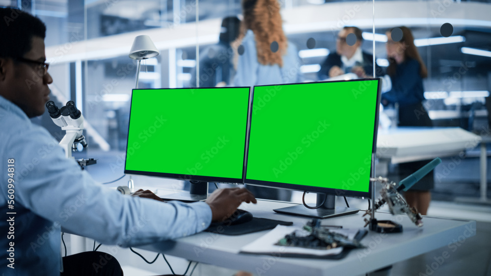 Software Developer Working on Computer with Green Screen Mock Up Display. Scientific Lab, Engineerin