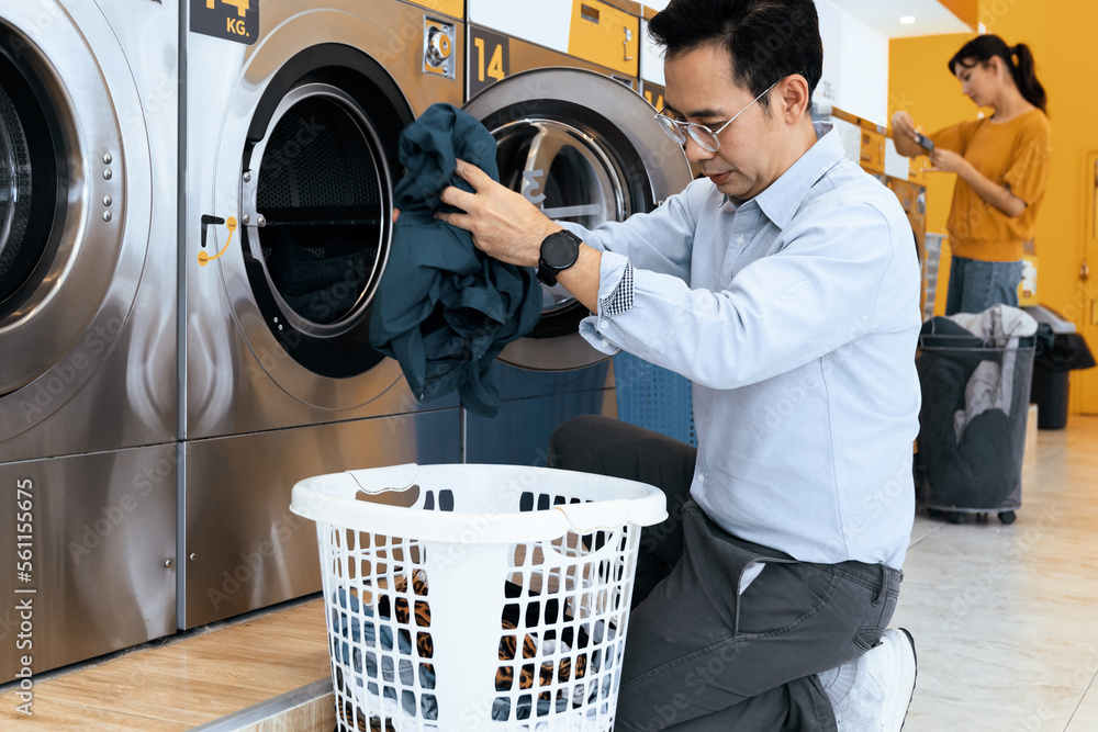 Asian people using qualified coin operated laundry machine in the public room to wash their cloths. 