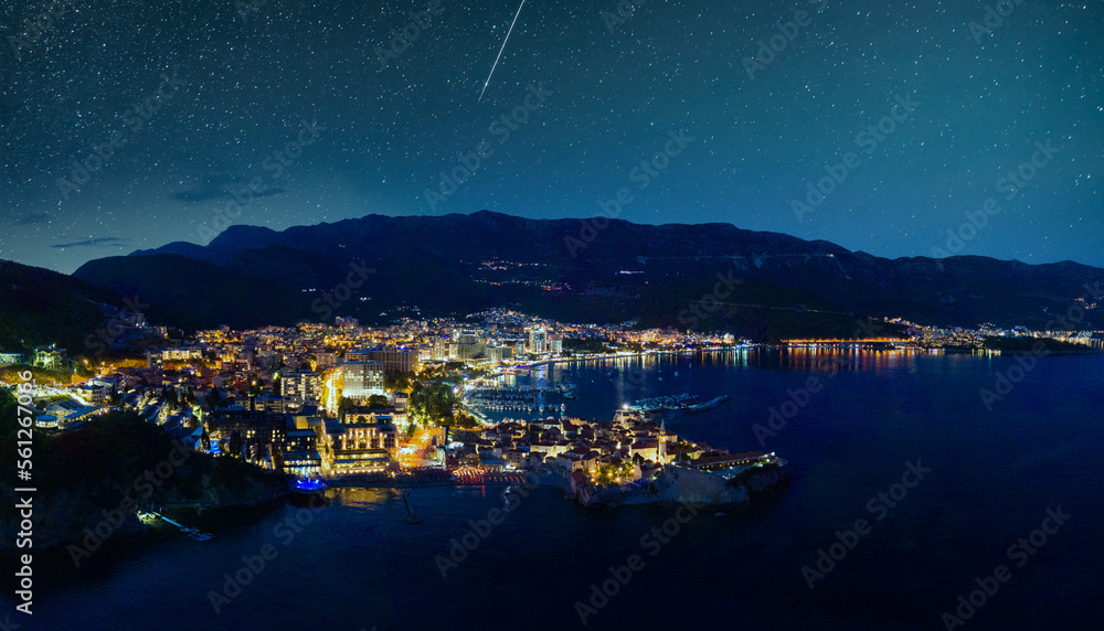 Panorama of night city with electric lights against the backdrop of slopes of the Montenegrin mounta