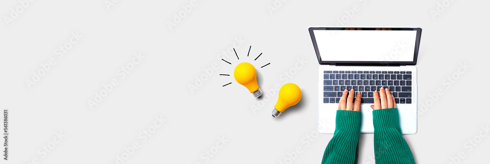 Person using a laptop computer and light bulbs - Flat lay