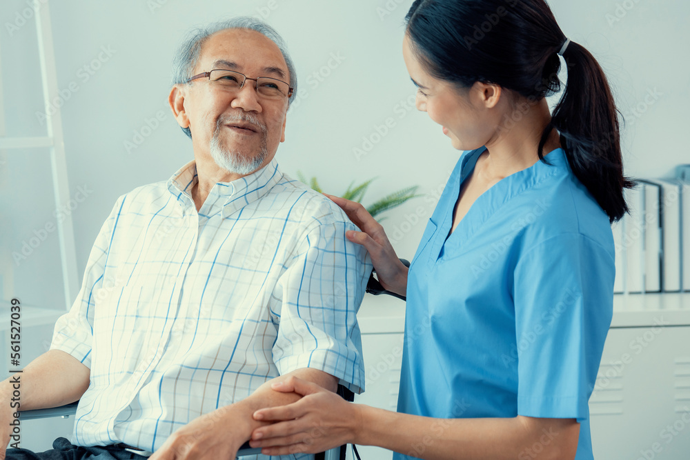 Happy positive asian nurse giving support and touching contented senior man with love. Nursing home 