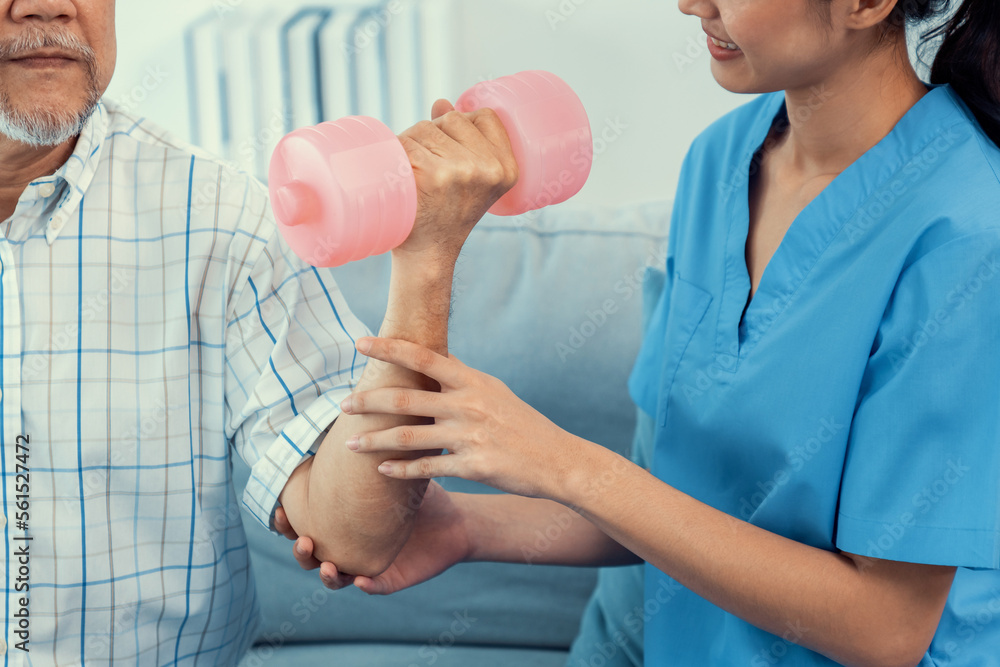 Contented senior patient doing physical therapy with the help of his caregiver. Senior physical ther