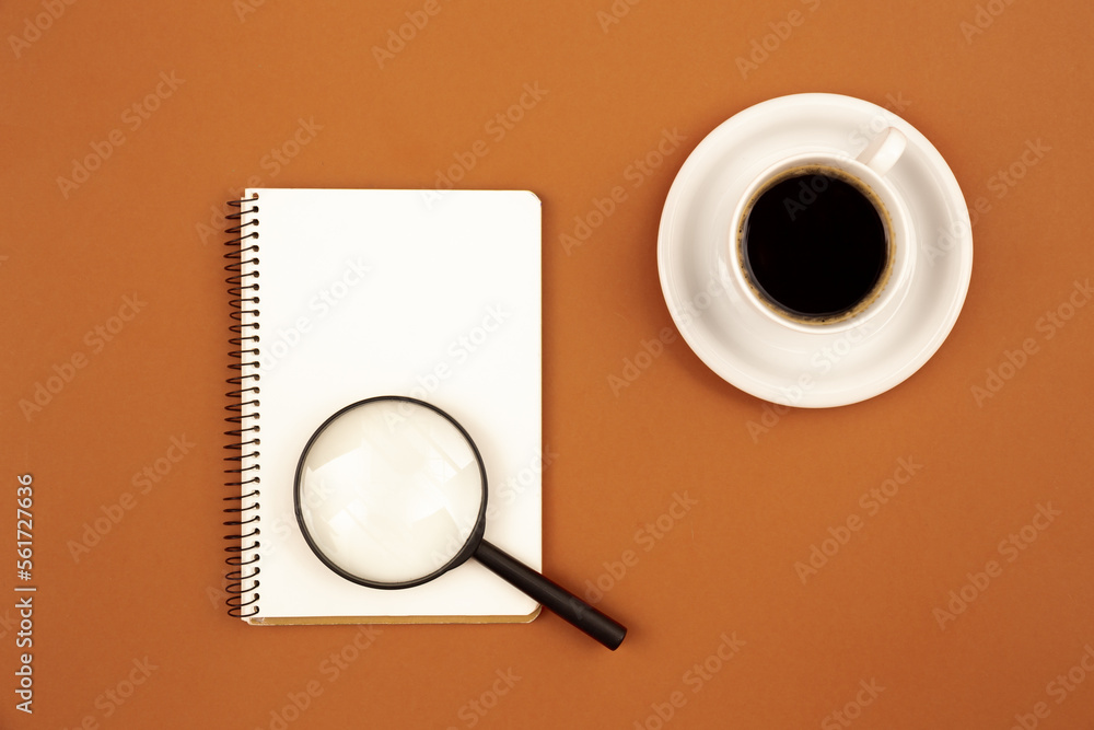 Blank notepad and coffee cup on a brown background, flat lay.