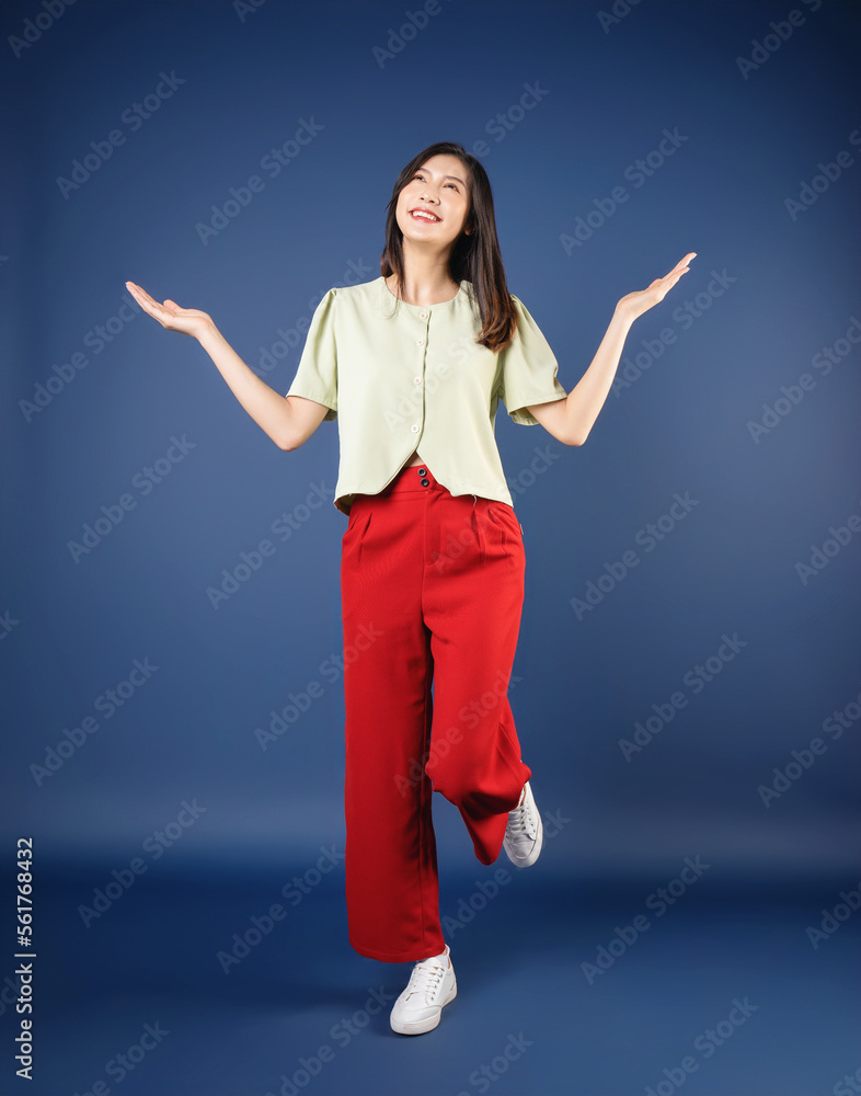 Full length image of young Asian woman standing on background