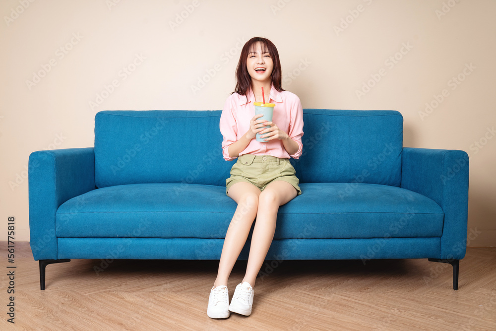 Image of young Asian woman sitting on sofa