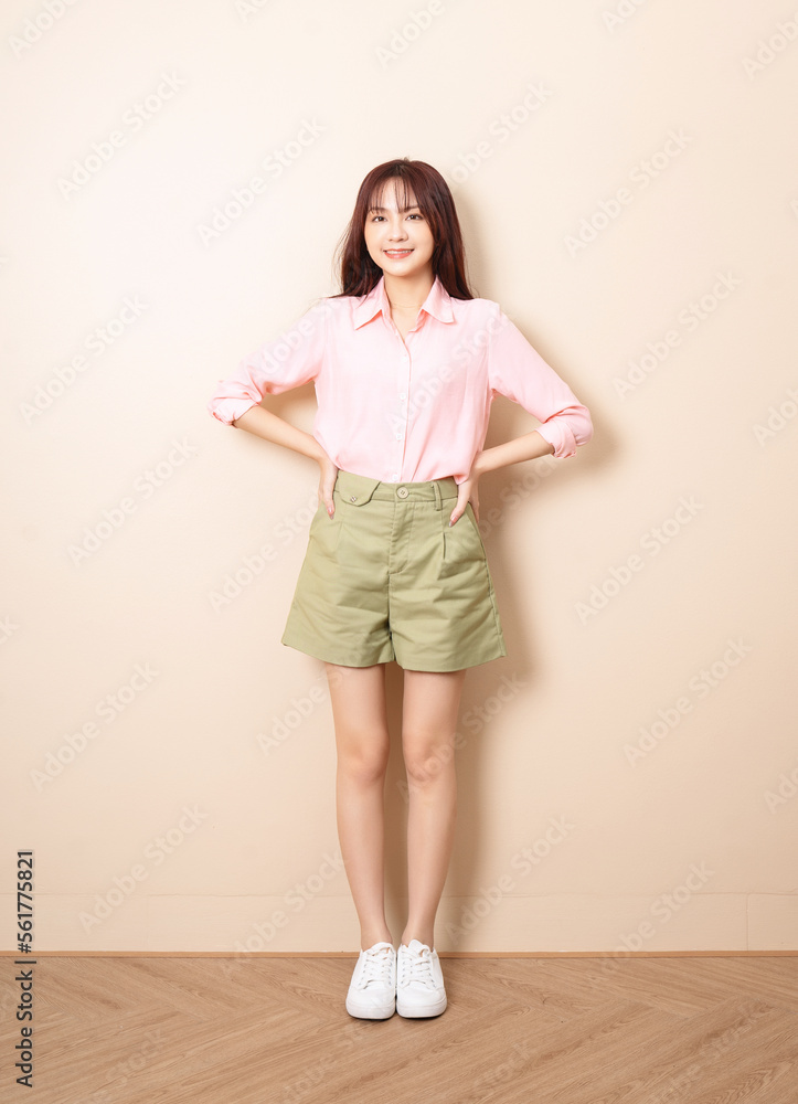 Full length photo of young Asian woman standing on background