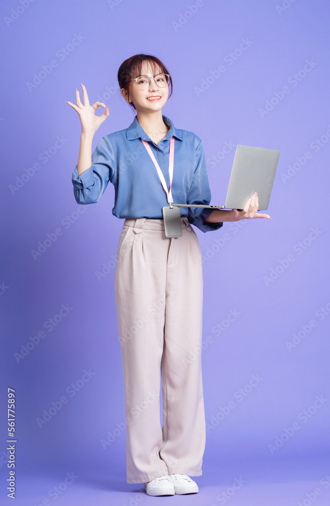 Photo of young Asian businesswoman holding laptop on background