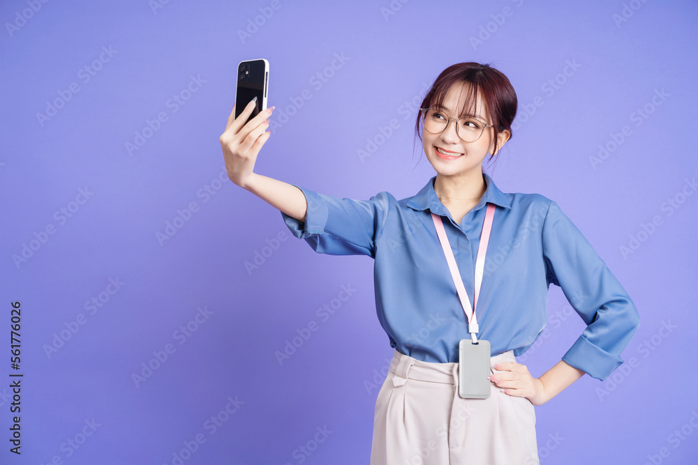 Photo of young Asian businesswoman holding smartphone on background