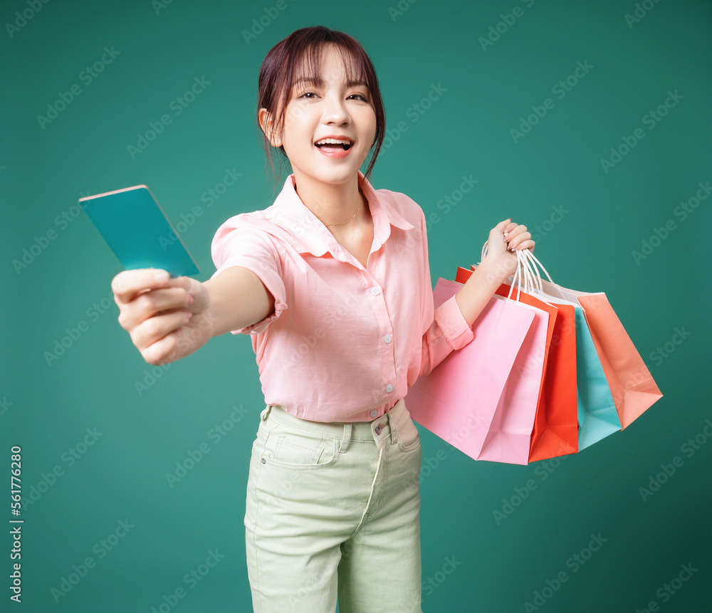 Image of young Asian girl holding shopping bag on background