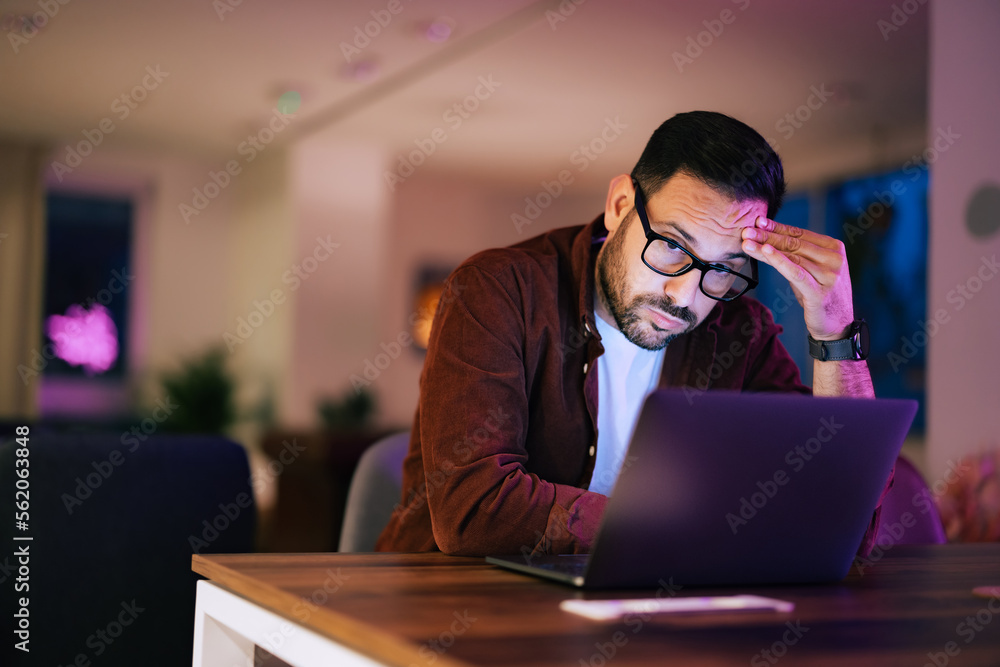 Businessman working late at night at his desk, using a laptop.