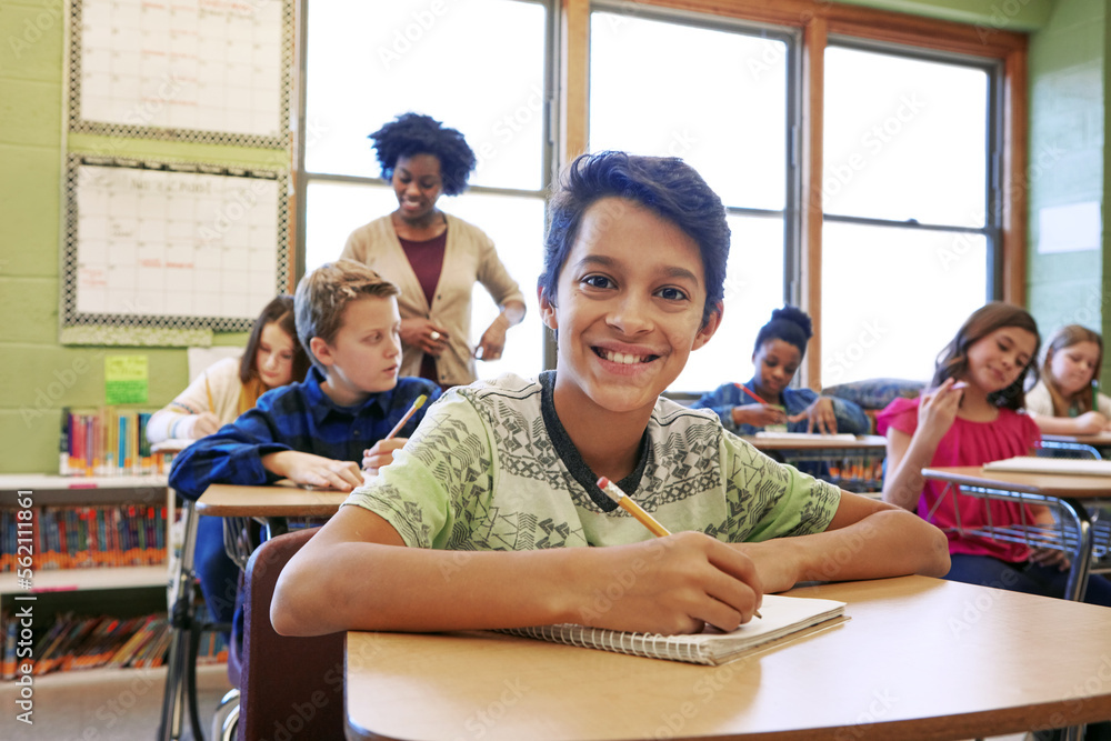 Happy, education portrait or kid in classroom writing in notebook for learning, research or study fo