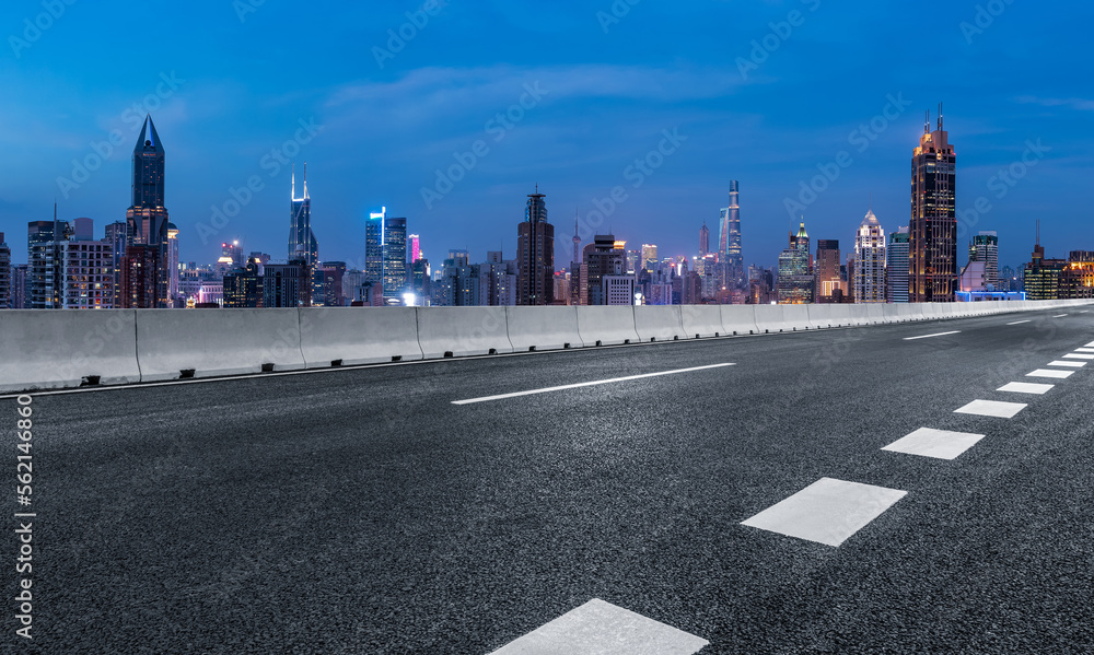 Asphalt road and city skyline with modern buildings at night in Shanghai, China.