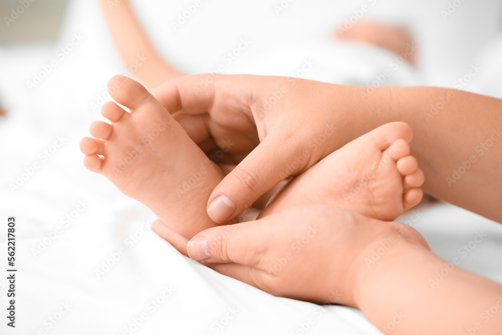 Mother massaging her babys feet in bedroom, closeup