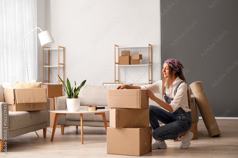 Young woman with cardboard boxes in living room on moving day